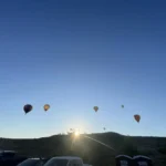 Photo of hot air balloons floating against a clear blue sky in Casper WY