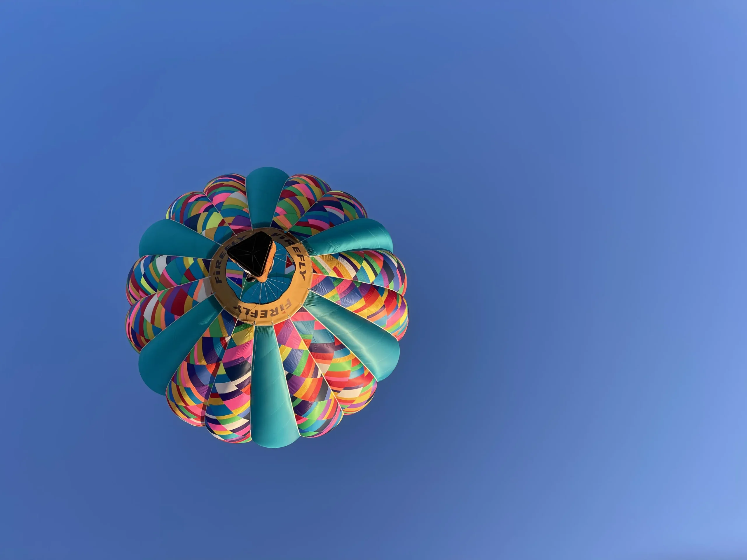 Photo of hot air balloon floating overhead against a clear blue sky in Casper WY