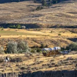 Image of a Wyoming landscape with people enjoying a covered wagon experience